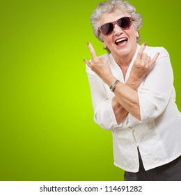 Senior woman wearing sunglasses doing funky action isolated on green background