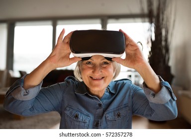 Senior woman wearing virtual reality goggles at home - Powered by Shutterstock