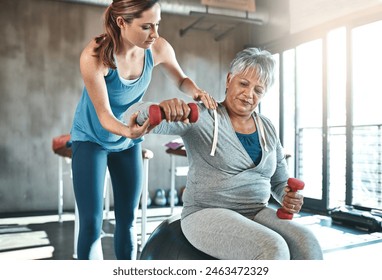 Senior woman, weights and helping with coach in gym for physio, arm exercise and rehabilitation on ball. Old female patient, instructor and workout equipment for arthritis with balance and dumbbells - Powered by Shutterstock