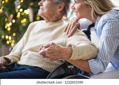 Une femme âgée en fauteuil roulant avec un visiteur de santé à la maison à Noël.