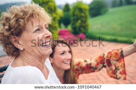 Senior woman in wheelchair laughing with her daughter