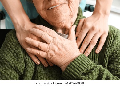 Senior woman in wheelchair holding caregiver's hand indoors, closeup - Powered by Shutterstock