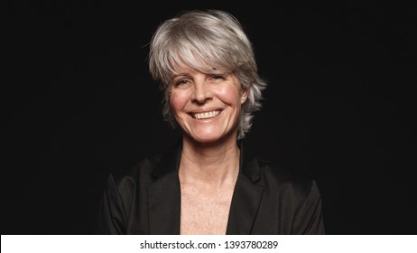 Senior Woman With White Hair Looking At Camera. Close Up Of Smiling Woman In Formal Wear Isolated On Black Background.