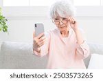 A senior woman who has presbyopia and has trouble seeing her smartphone