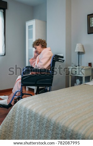 Senior woman in a wheelchair alone in a room