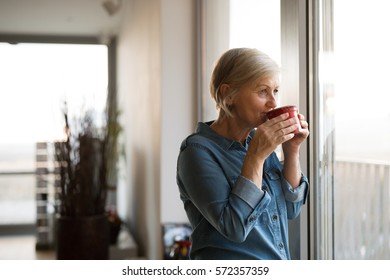 Senior Woman At The Window Holding A Cup Of Coffee