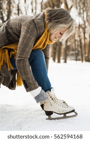 Senior Woman In Winter Clothes Putting On Old Ice Skates.