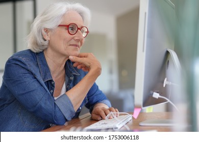 Senior Woman Working On Desktop Computer At Home