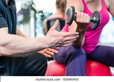 senior woman working out with dumbbells with personal trainer - Powered by Shutterstock