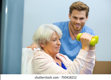 senior woman working out with dumbbells with personal trainer
