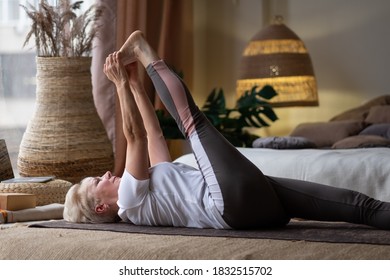 Senior Woman Working Out, Warming Up Using Yogic Belt, Lying In Yoga Supta Padangushthasana, One Leg Lift Exercise, Reclined Variation Of Extended Hand To Big Toe Pose At Home.