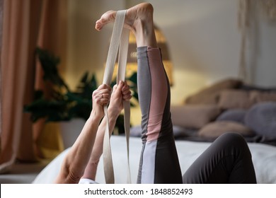 Senior Woman Working Out, Warming Up Using Yogic Belt, Lying In Yoga Supta Padangushthasana, One Leg Lift Exercise, Reclined Variation Of Extended Hand To Big Toe Pose At Home.