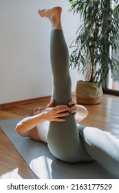 Senior Woman Working Out, Warming Up, Lying In Yoga Posture. One Leg Lift Exercise, Reclined Variation Of Extended Hand To Big Toe Pose At Home