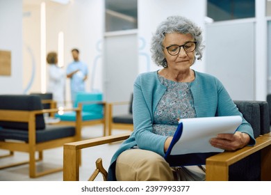 Senior woman writing her data in medical documents in waiting room at the clinic. - Powered by Shutterstock