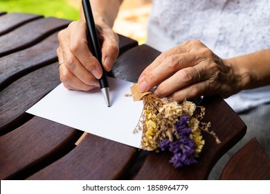 Senior Woman Writing Postcard And Preparing Present For Christmas And New Year Celebration