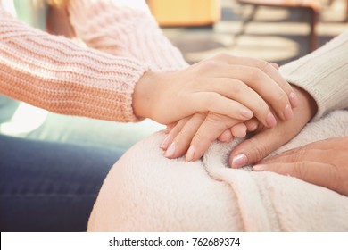 Senior Woman And Young Caregiver Holding Hands, Closeup