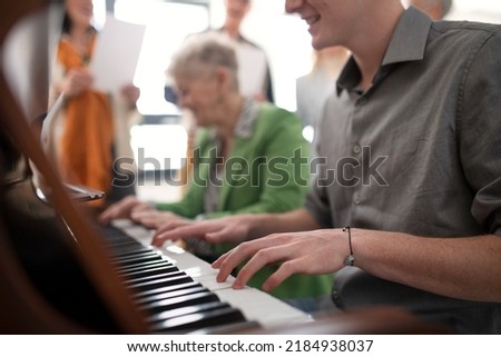 Senior woman with young teacher playing at piano in choir rehearsal.