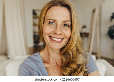 Senior woman-blogger with long golden hair, pretty freckled face, blue eyes and charming smile making selfie or recording stories for social network page, looking friendly and happy - Powered by Shutterstock