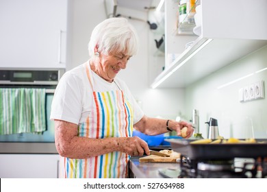 Senior woman/grandmother cooking in a modern kitchen (shallow DOF; color toned image) - Powered by Shutterstock