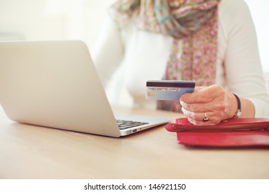 Senior Woman's Hand Holding A Credit Card While In Front Of The Laptop Shopping Online