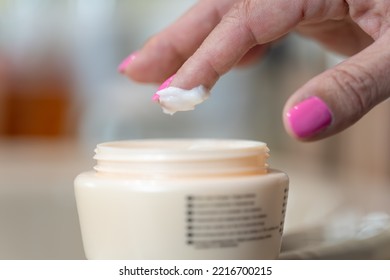 Senior Woman's Hand Picking Cream With Her Finger For Personal Skin Care.