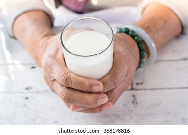 Senior Woman's Hands Holding A Glass Of Milk.