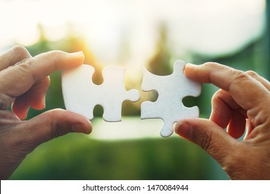 senior woman's hands trying to connect jigsaw puzzle pieces together,  - Powered by Shutterstock