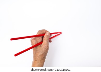 Senior Woman's Left Hand Using Red Plastic Chopsticks Isolated On White Background