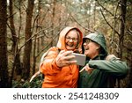 Senior women friends laughing together on forest hike in raincoats