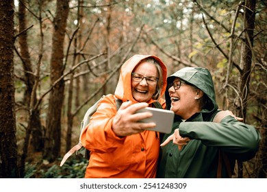 Senior women friends laughing together on forest hike in raincoats - Powered by Shutterstock