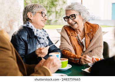 Senior women laughing while having breakfast with group of friends at cafeteria bar. Elderly lifestyle and friendship concept. - Powered by Shutterstock