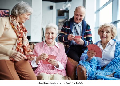 Senior women and man with cards playing bridge at leisure