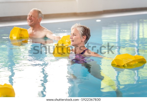 Senior women and men in Rehabilitation training in\
a water gymnastics class