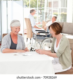 Senior Women Playing Cards While Their Husbands Are Talking