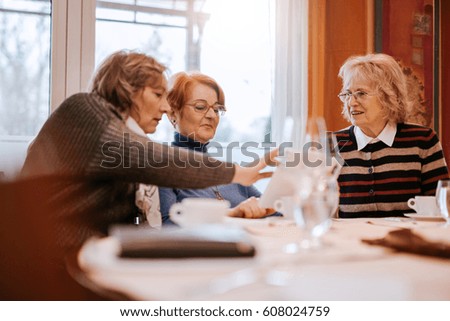 Senior Women In A Restaurant Using A Tablet