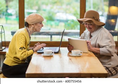 Senior women sitting in cafe. Tablet and notebook pc. Features of social networking. - Powered by Shutterstock