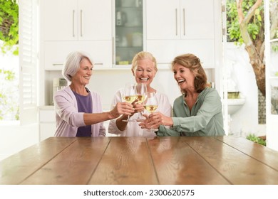 Senior women toasting wine glasses in kitchen - Powered by Shutterstock