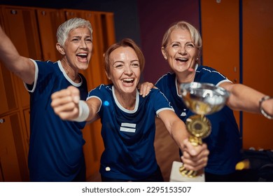 Senior women and young woman together celebrating first place in dressing room. Female basketball team winning gold cup, first place.  - Powered by Shutterstock