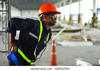 Senior worker with backache at construction site in warehouse.