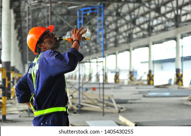 Senior worker having alcoholic drinks in the construction site at warehouse.