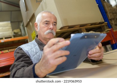 Senior Worker Holding Clipboard In Warehouse