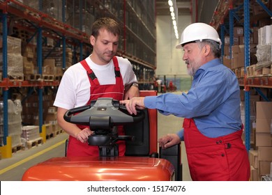 A Senior Worker Teaching His Junior The Operation Of A Fork Lift Vehicle In A Factory