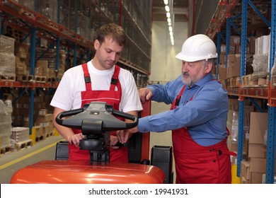 A Senior Worker Teaching His Junior The Operation Of A Fork Lift Vehicle In A Factory