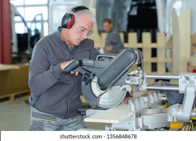 senior worker using circular saw in workshop