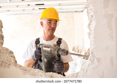 Senior worker using drill at contruction site, closeup