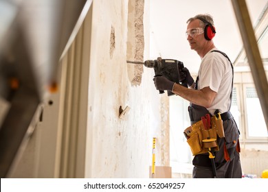 Senior Worker Using Drill At Contruction Site, Closeup