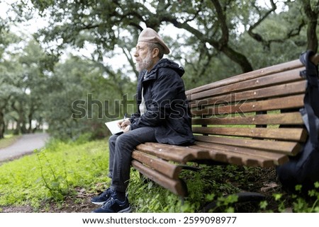 Senior writer taking notes while sitting on park bench