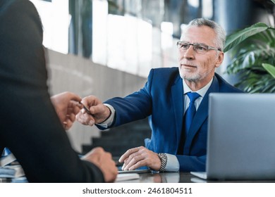 Senior and young businessmen entrepreneurs investors partners coworkers having a business meeting in modern office restaurant. Two men discussing signing the contract - Powered by Shutterstock