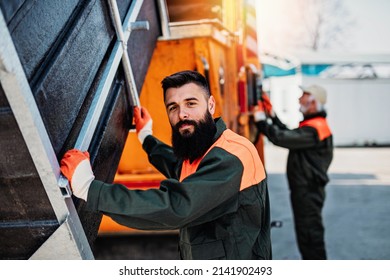 Senior and young garbage men working together on emptying dustbins for trash removal. - Shutterstock ID 2141902493