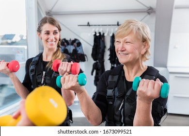 Senior and young woman during wireless ems training with weights